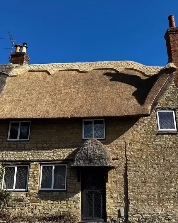 Front of a stone cottage with new thatch and thatched porch, 2024