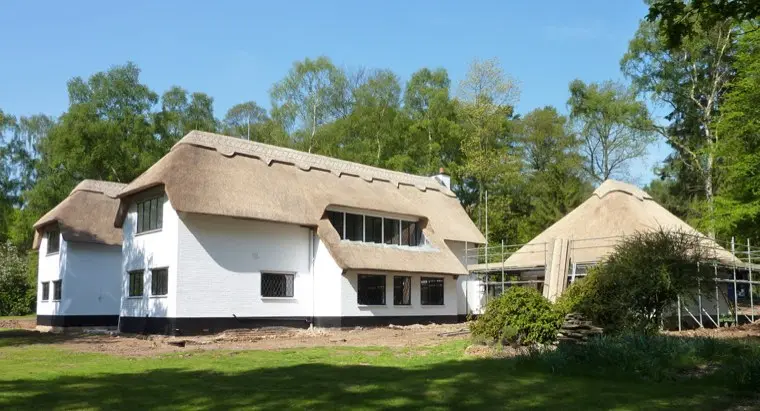 White house with eyebrow dormers among trees